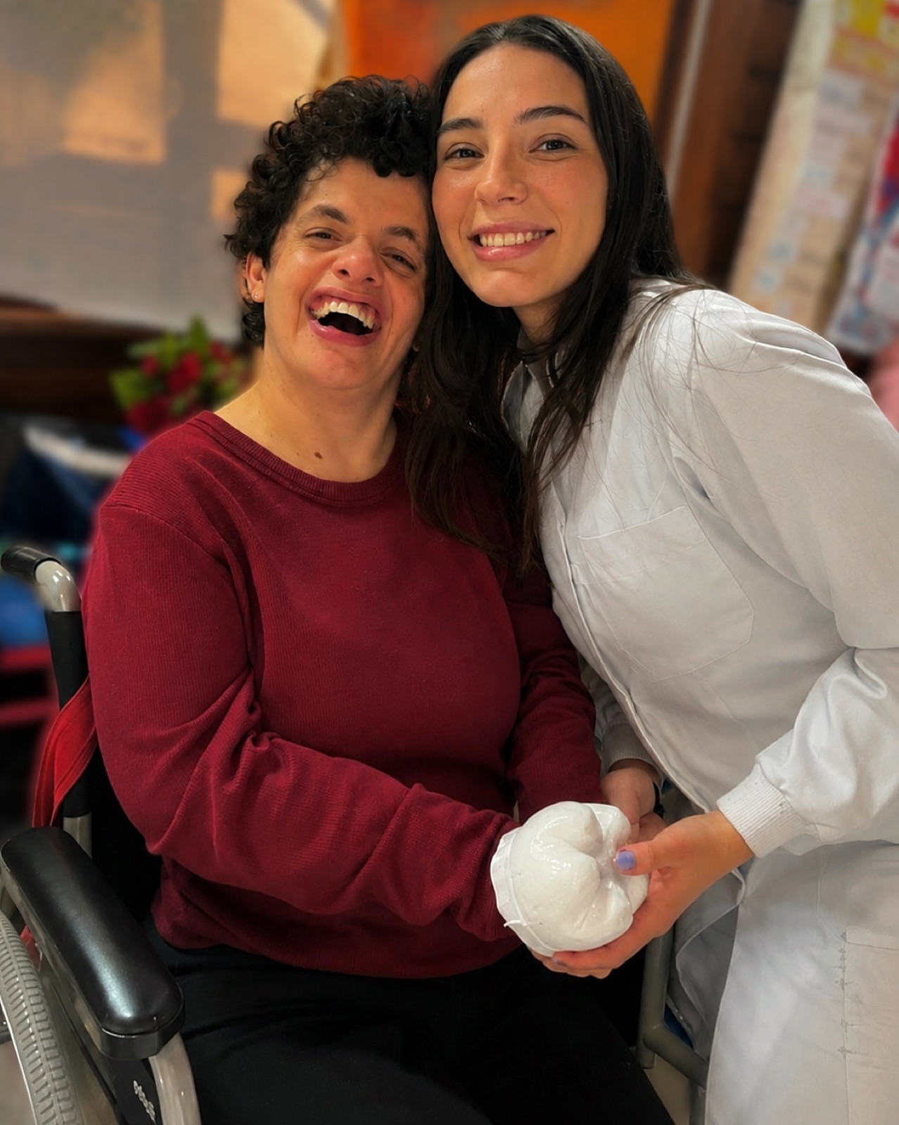 Dra. Mariana abraçando uma paciente que sorri, segurando uma pelúcia de dente